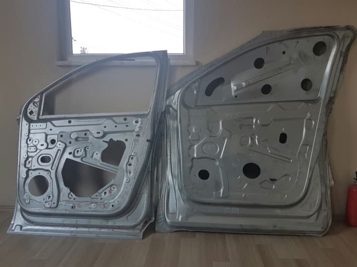 Pair of stamped automotive door panels standing against a wall