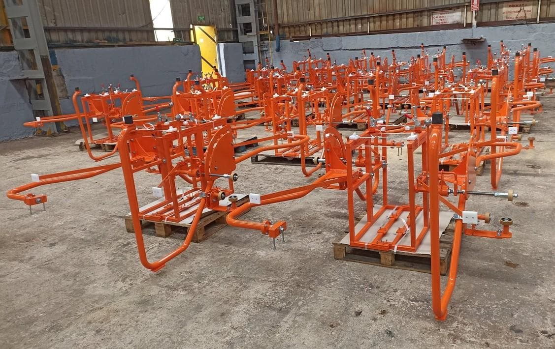 Rows of fabricated orange steel jig and fixture frames on a workshop floor