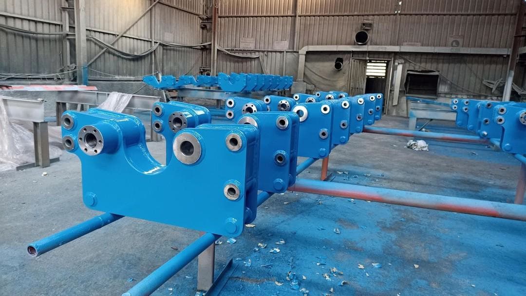 Blue powder-coated precision machined hydraulic components lined up in a workshop