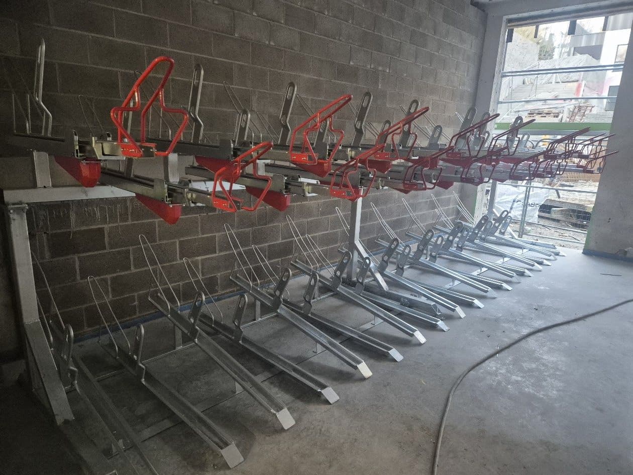 Two-tier bicycle parking racks installed against a block wall, with red and silver frames