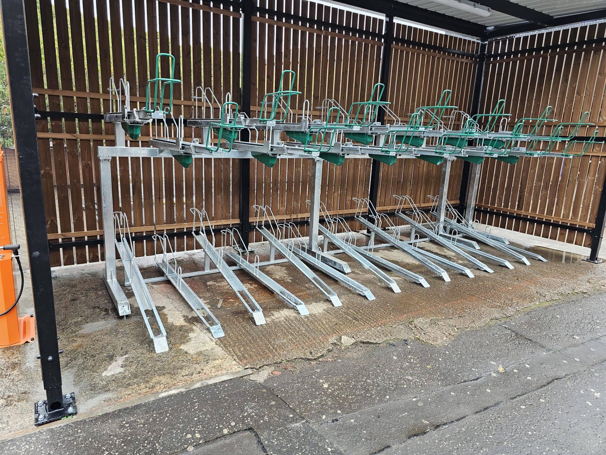 Two-tier bicycle parking racks with green accents installed under a covered shelter