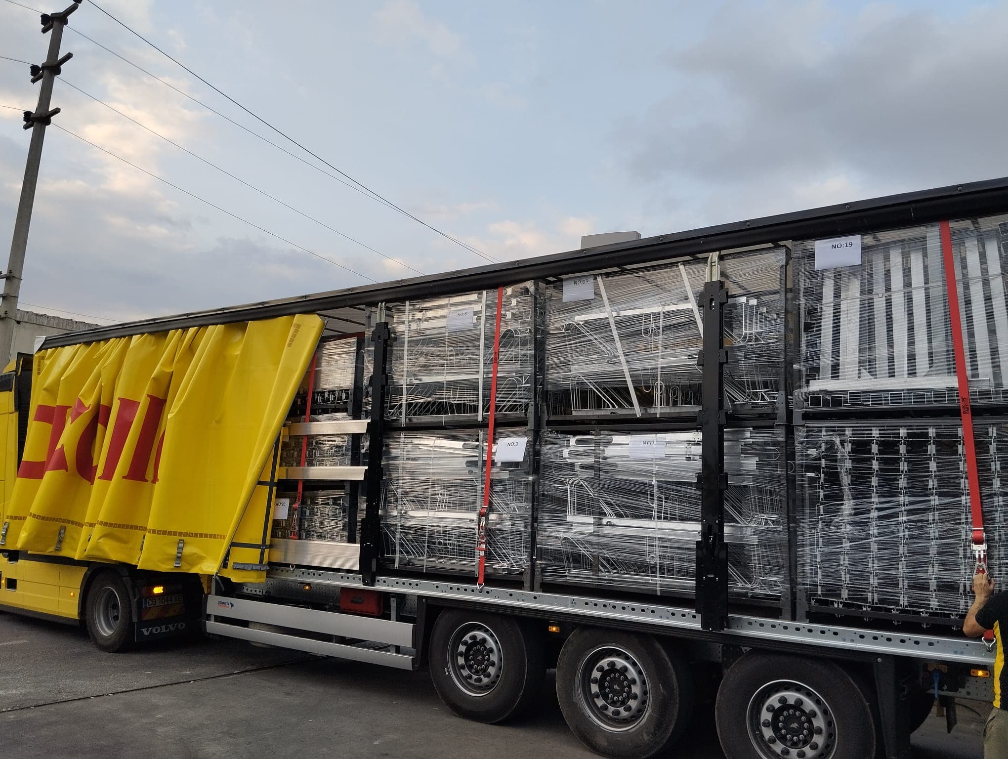 Curtain-side trailer loaded with shrink-wrapped steel pallets numbered for shipment