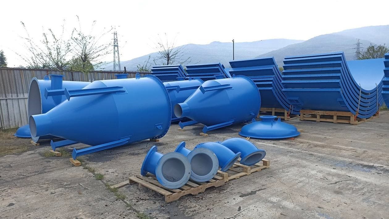 Blue-painted industrial tanks, hoppers, and ductwork staged in a yard