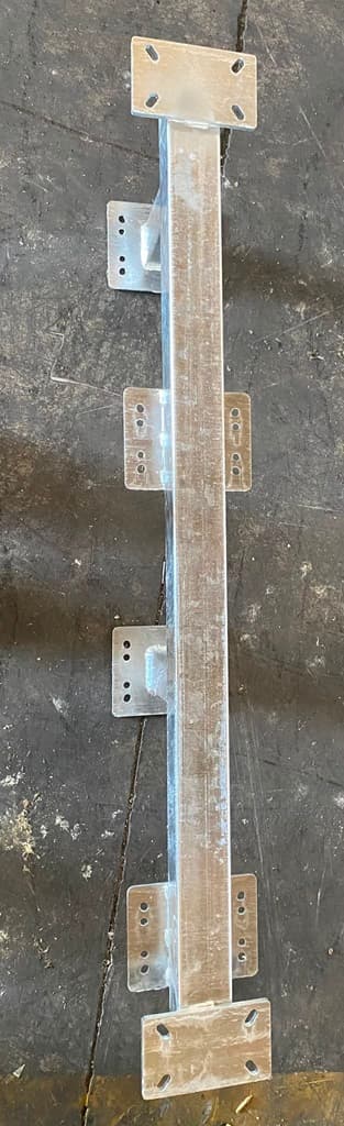 Close-up of a galvanized steel post with mounting brackets along its length