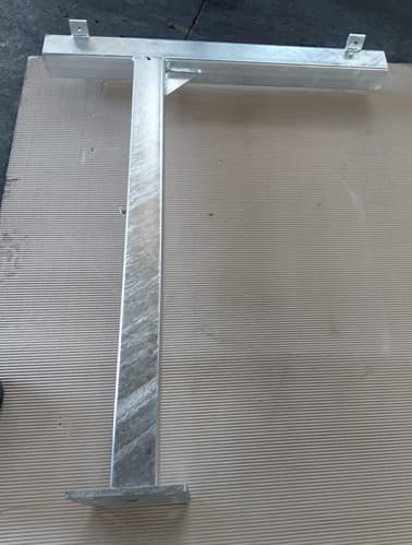 Galvanized steel T-shaped bracket component on a workshop floor
