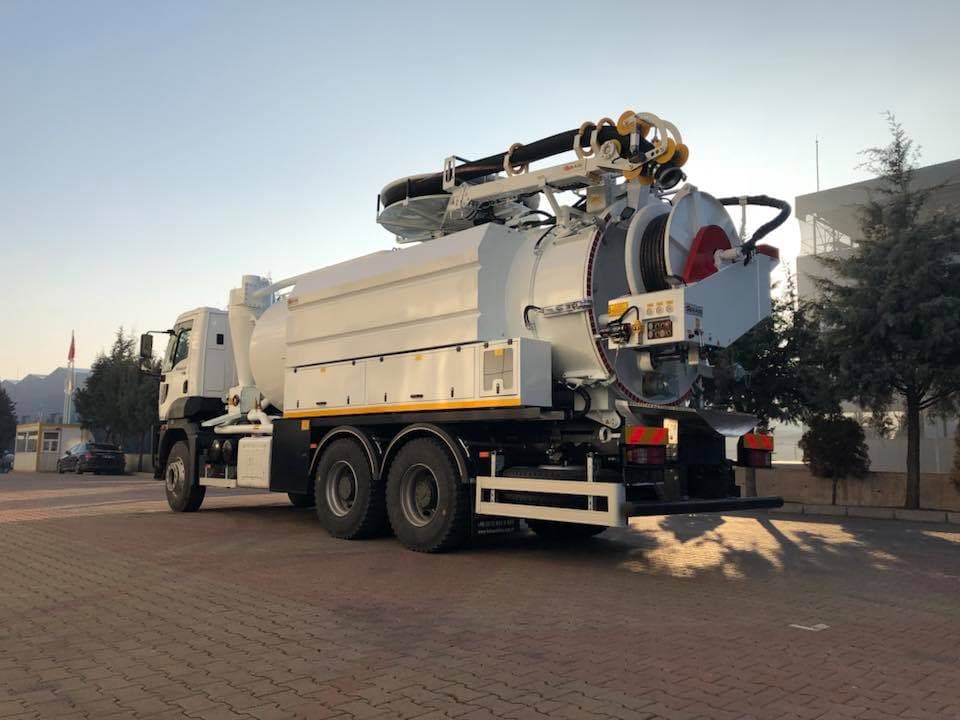 White vacuum tanker truck with a rear-mounted hose reel and crane arm