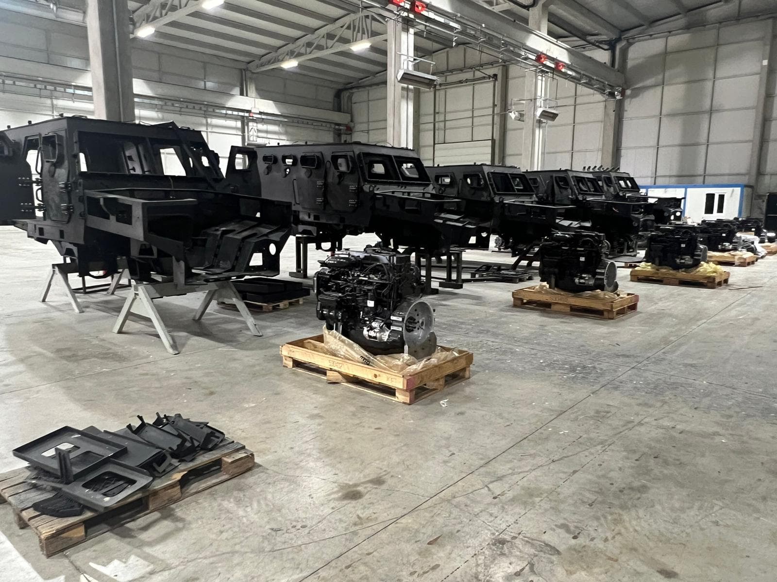 Rows of fabricated armored vehicle chassis and cab frames in a production hall